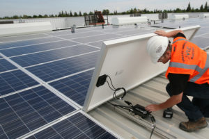 solar panel installation with electrician wearing fluorescent suit and white helmet