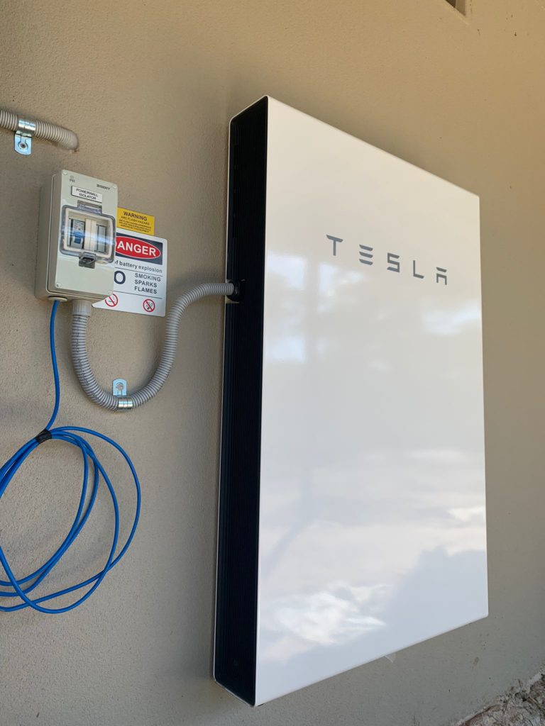 picture of white tesla powerwall solar battery attached to a wall in a house