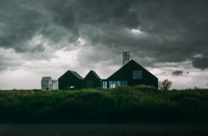 single house in the middle of field with dark rain clouds and storm