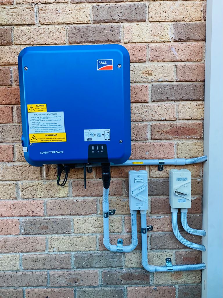 sma sunny tripower string inverter blue against brick wall