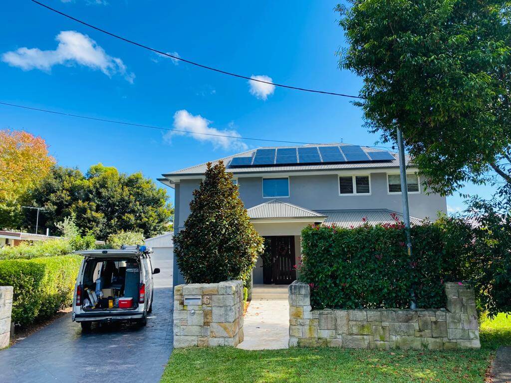 house with solar panels on roof and van outside